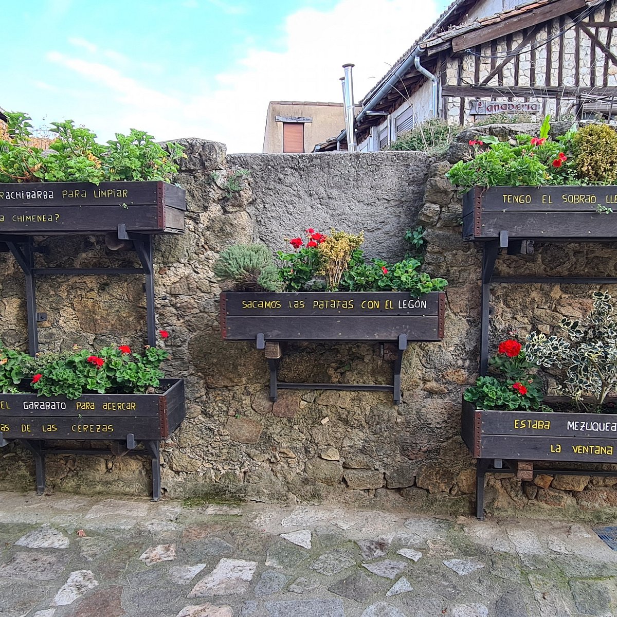 Flower boxes with traditional sierra words painted on them in a cobbled street.